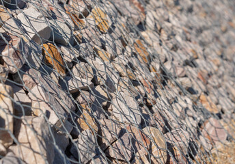 Gabion stone wall construction close up. New stone fence in wire grid, iron cage with rocks