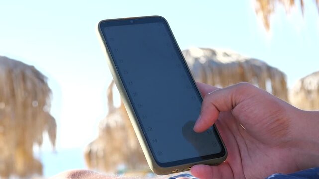 A person enjoys beach relaxation while playing a simple prediction game on his mobile device. The trial and error gameplay captures lighthearted entertainment moments, ideal for vacation content and