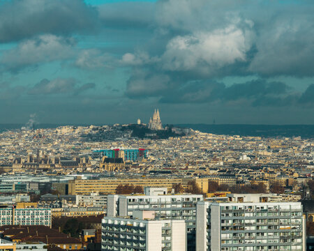 Aerial view of the Sacr&eacute;-Coeur Basilica standing majestically atop Montmartre, overseeing the urban sprawl under a sky of shifting clouds, Paris, Ile-de-France, France.