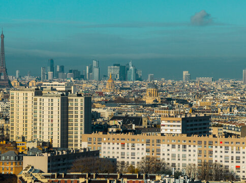Aerial view of the iconic Eiffel Tower piercing the skyline, juxtaposed against modern skyscrapers and historic domes, bathed in the soft glow of a winter day., Paris, Ile-de-France, France.