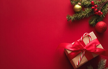 Brown gift box tied with red ribbon and candy cane enjoying a festive display with pine branches and ornaments