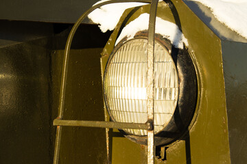 Headlight on a Dark Military or Heavy Vehicle Surrounded by Snow
