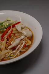 spicy chicken noodle bowl with peppers, bean sprouts, carrot ribbons, savory broth, glossy chili oil, casual restaurant serving,