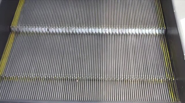 Metal steps of a moving escalator with yellow safety lines