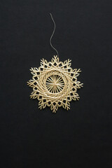Snowflakes are made of straw on a black background. Straw snowflakes. Christmas decor. Top view. Straw weaving. Lutsk, Ukraine