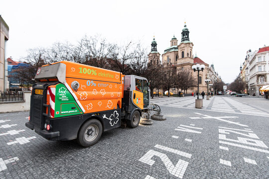 Prague, czech republic - december 2, 2025: electric street sweeper cleaning cobblestones with st. Nicholas church in the background