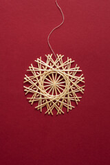 Straw snowflake. Snowflake are made of straw on a red background. Christmas decor. Top view. Straw weaving. Lutsk, Ukraine