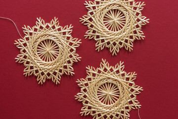 Straw snowflakes. Snowflakes are made of straw on a red background. Christmas decor. Top view. Straw weaving. Lutsk, Ukraine