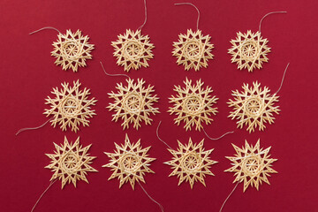 Straw snowflakes. Snowflakes are made of straw on a red background. Christmas decor. Top view. Straw weaving. Lutsk, Ukraine