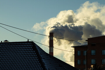 Thick Industrial Smoke Billowing from a Tall Factory Chimney Above Urban Rooftops