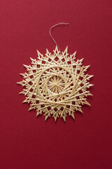 Straw snowflake. Snowflake are made of straw on a red background. Christmas decor. Top view. Straw weaving. Lutsk, Ukraine