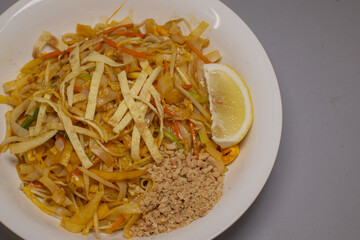 noodles with crushed peanuts and lemon wedge, egg ribbons and bean sprouts mingle with tamarind glaze, bright citrus accent
