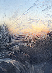 Beautiful ice patterns and sunlight on winter window glass, close-up natural texture