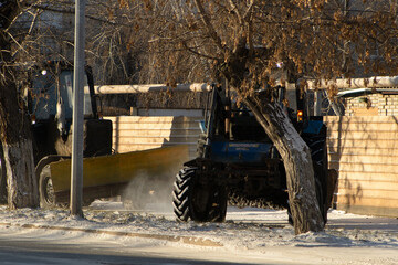Rear View of a Heavy Blue Tractor with Front Loader on a Snow-Dusted Roadside