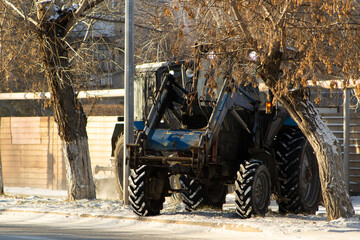 Rear View of a Heavy Blue Tractor with Front Loader on a Snow-Dusted Roadside