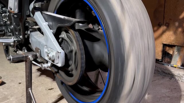 Garage Technician Testing Motorcycle Wheel Balance Amidst Motion Blur And Industrial Environment