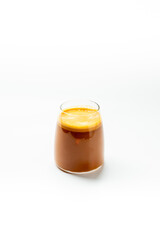 A close-up vertical shot of an iced coffee with foam served in a clear, stemless glass against a white background. Perfect for beverage and cafe promotions