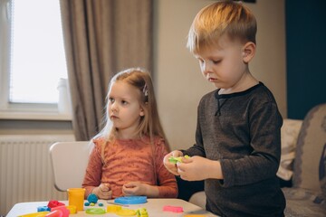 Obraz premium Children playing with colorful playdough at home