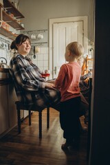 Young mother smiling, talking to son in kitchen