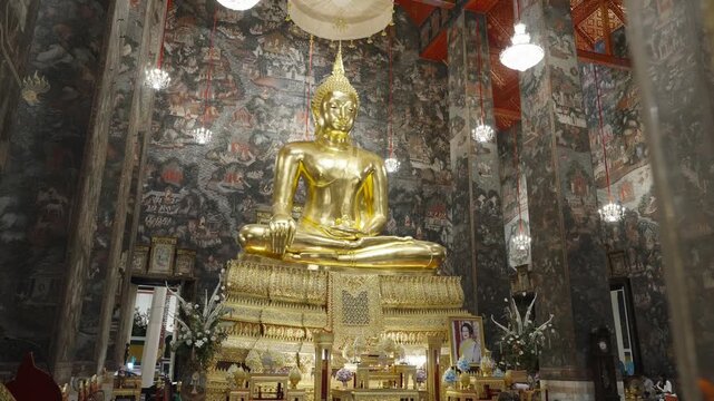 Majestic interior view of a Thai temple featuring a large golden Buddha statue and ornate decorations.