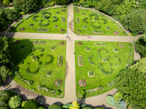 Aerial view of symmetrical garden quadrants bursting with vibrant green lawns, meticulously trimmed hedges, and pathways meeting in the center, Bury Saint Edmunds, England, United Kingdom.
