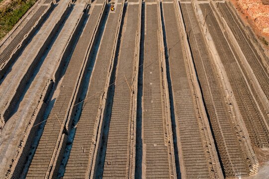 Aerial view of rows of drying bricks create an abstract pattern of light and shadow, a geometric landscape of industry, Aminbazar, Dhaka Division, Bangladesh.