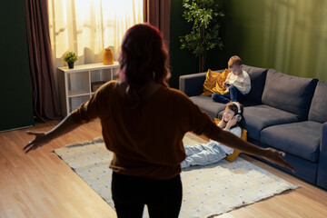 Mother scolding her son and daughter addicted to using smartphone and headphones, ignoring her and playing video games or listening music