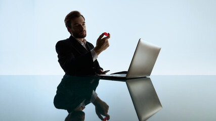 Man holding red dice while evaluating risk in online casino session. Concept of gambling focus, betting choices, psychological pressure and emotional tension in digital play.