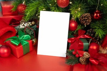 Mockup of blank white card on red background with Christmas decorations and tree, with clipping path