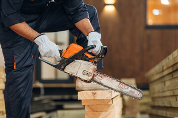 Using a chainsaw. Close-up of a carpenter working with wood using professional tools in a workshop