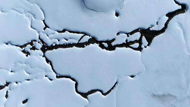 Aerial view of stark white snow contrasting against the dark earth in a textured landscape, Wildhaus-Alt Saint Johann, St. Gallen, Switzerland.