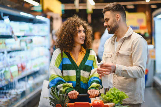 Young couple grocery shopping checking items in supermarket - Powered by Adobe