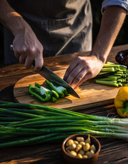 A chef meticulously slices fresh green bell peppers on a wooden cutting board, surrounded by an array of vibrant vegetables and ingredients.