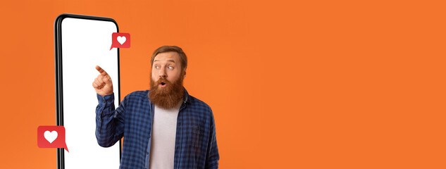 A man with a beard and plaid shirt looks surprised as he points at a smartphone. Speech bubbles with hearts appear, suggesting he is engaging with social media.