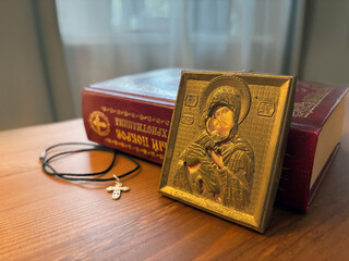 Orthodox icon and a cross on a wooden table,Book of Prayers. Madonna (Mary) of Jerusalem and a child (Jesus Christ) 