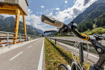 composizione visiva panoramica, con parte di bici da strada in primo piano, appoggiata ad un...