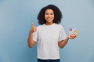 Young woman showing pills and thumbs up