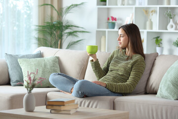 Woman in green relaxing drinking coffee in a house