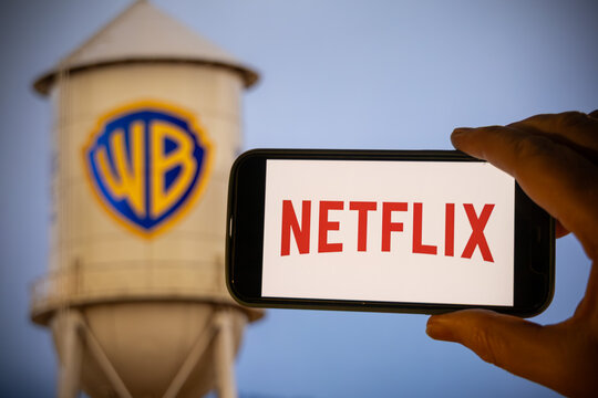 Los Angeles, 5 Dec 2025. Hand holding a phone with the Netflix logo in front of the iconic Warner Bros. water tower, following news of a proposed merger.