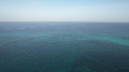 Aerial view of ocean with clear blue water and sky for travel and vacation concept