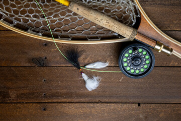 vintage fly fishing rod with wooden framed fishing net. streamer flies in foreground on wooden...