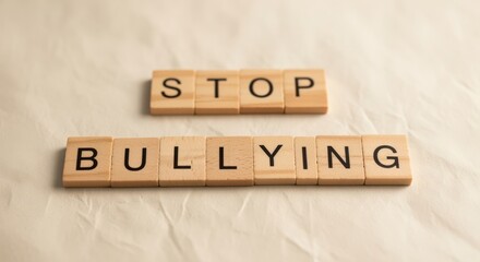 Wooden blocks arranged to spell STOP BULLYING on beige paper background with soft lighting, concept of anti-bullying awareness, kindness, empathy and social responsibility