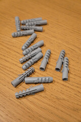 Gray plastic wall anchors on a wooden surface, ready for construction