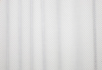 ​An abstract texture of white tulle or curtains, creating a delicate, airy background for design and interiors. The fine mesh weave with a small geometric pattern forms soft vertical folds. © Олег Струс