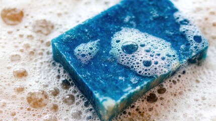 Blue soap bar rests in white foam on a clean surface during product showcase