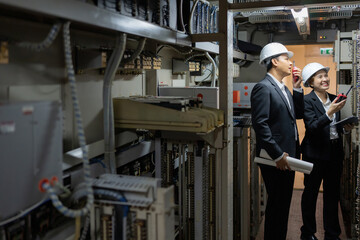 In an industrial plant, two experts analyze each part of a blueprint to verify that the mechanical layout, automation routes, and structural diagrams comply with strict engineering standards.