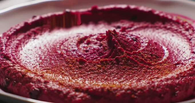 Vibrant beetroot dip being garnished with spices