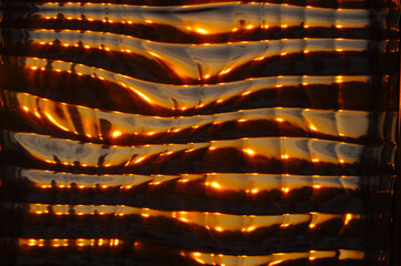 Abstract golden glass texture with reflections of sunset light