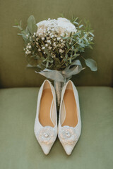 Elegant wedding flowers and bridal shoes arranged on a refined green background. Soft, stylish composition ideal for wedding themes, bridal details, and romantic celebrations.