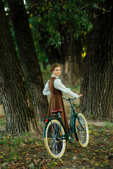 Naklejka premium Blonde woman with elegant hairstyle in a beautiful vintage dress with bicycle poses outdoors in a natural setting, showcasing timeless fashion, grace, and soft, dreamy atmosphere with stunning details